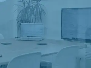Blue office shot of an empty meeting room 1 with laptop and main screen set up on google analytics