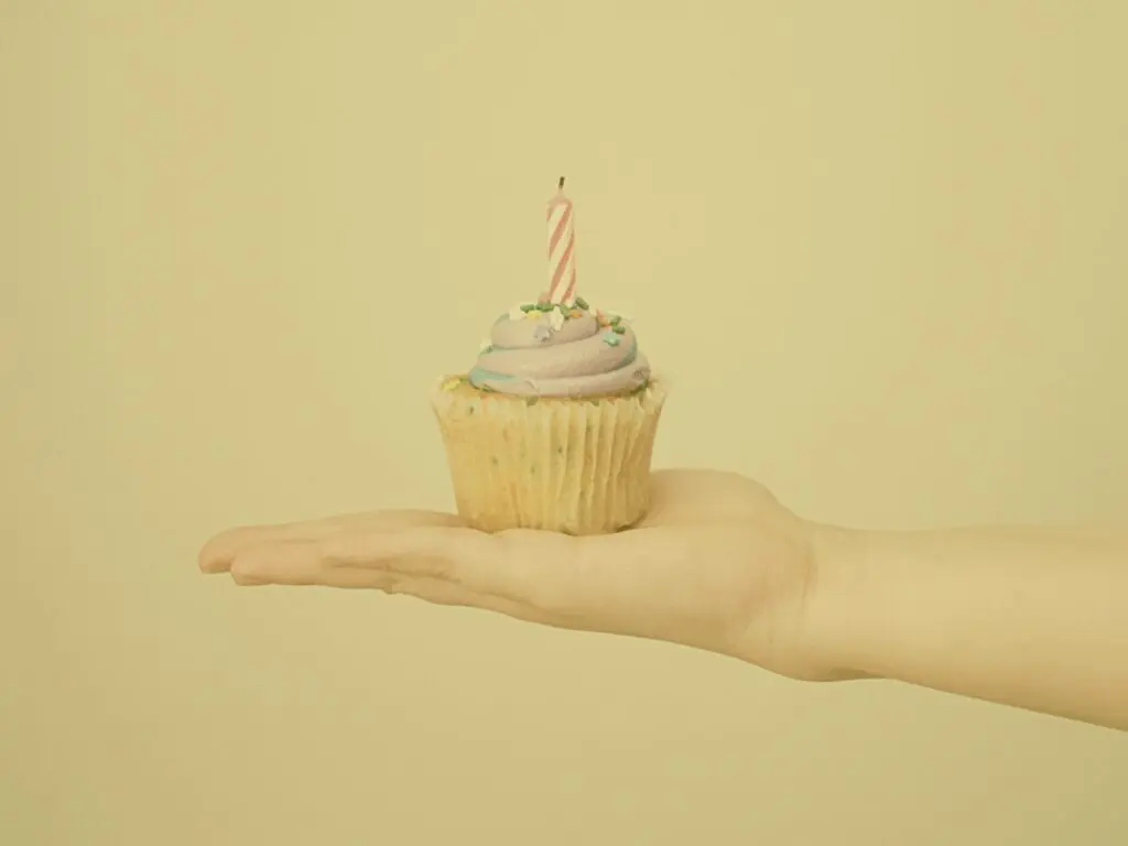 Yellow birthday cupcake with frosting and candle