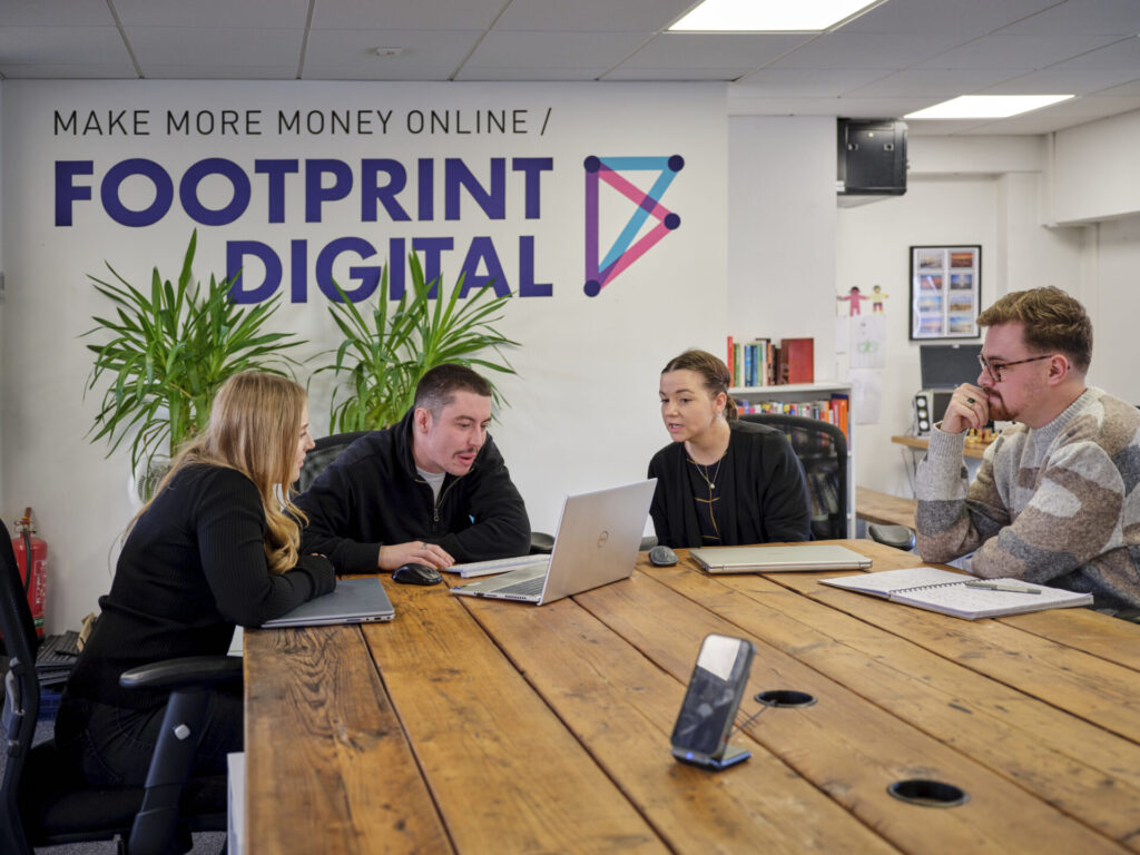 Full colour team shot in main office with Issy, Kieran J, Crystal, and Kieran M sat around desk